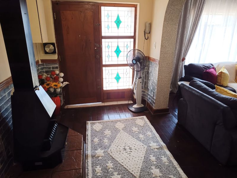 Entrance area featuring a stained glass front door, timber flooring, stone-look wall cladding, and a freestanding fireplace with a tiled hearth.