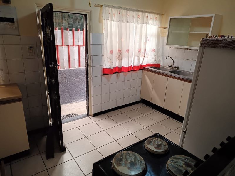 A functional kitchen featuring tiled flooring, built-in cabinetry, a double sink, and direct access to an exterior area.