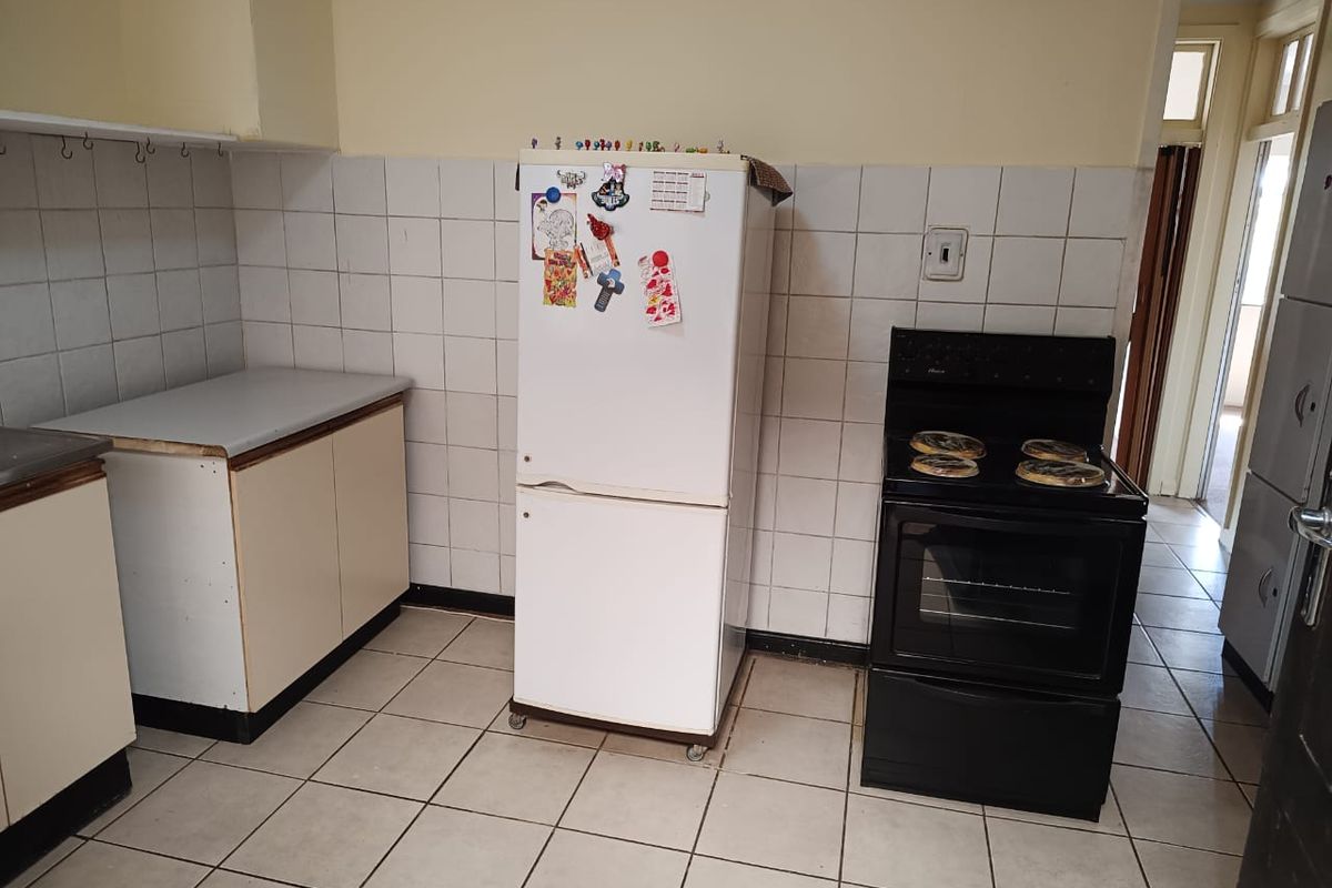 A functional kitchen featuring tiled flooring, a tiled splashback, and built-in cabinetry with an integrated electric stove and oven.
