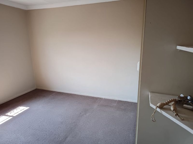 An empty bedroom featuring neutral walls, carpeted flooring, and built-in shelving units.