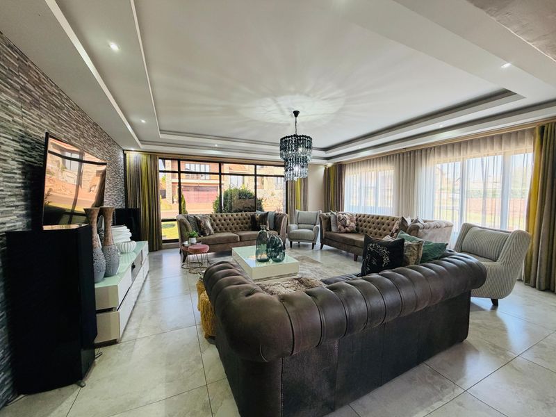 Spacious living room featuring a stone accent wall, recessed ceiling with downlights, large glass sliding doors, and polished tile flooring.