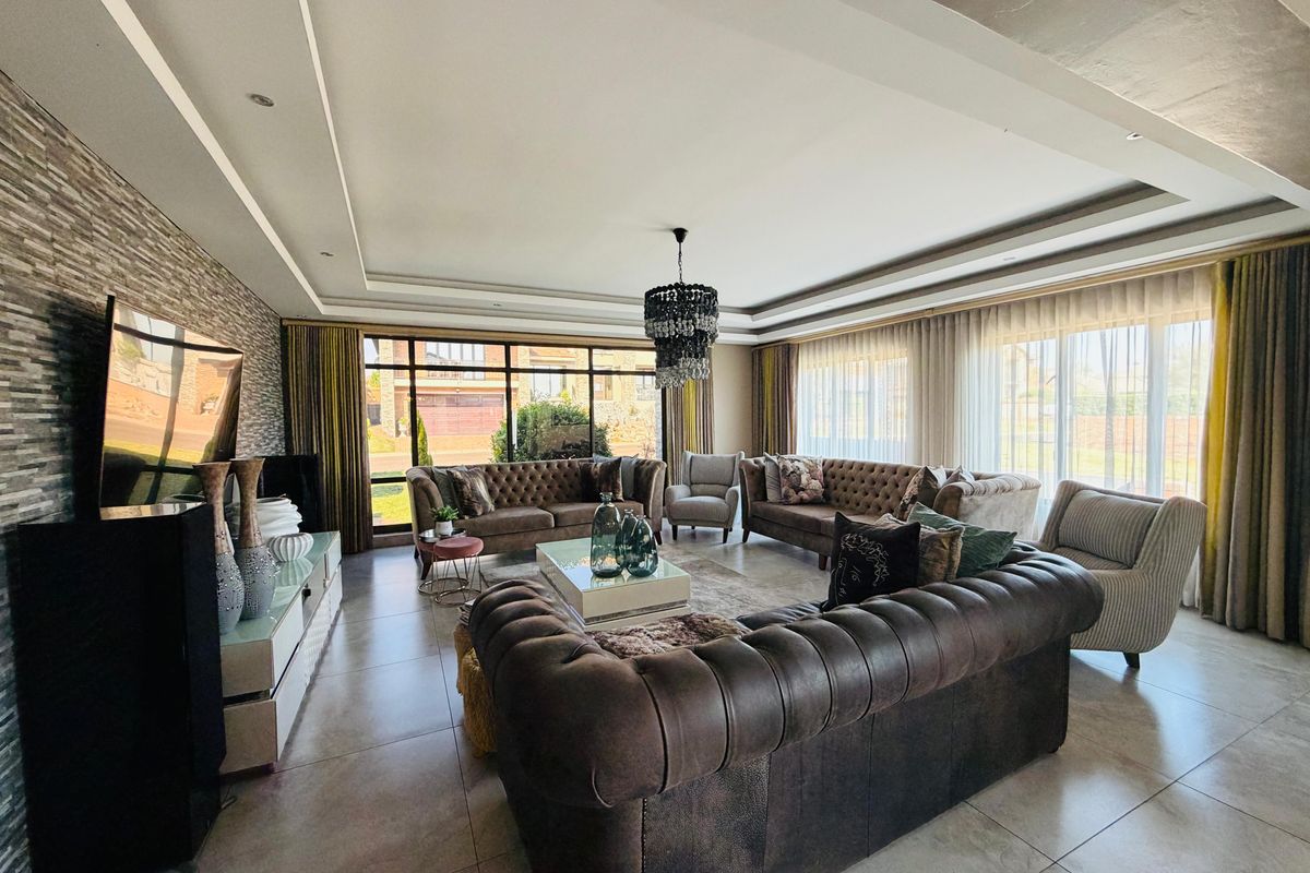 Spacious living room featuring a stone accent wall, recessed ceiling with downlights, and large windows providing ample natural light.