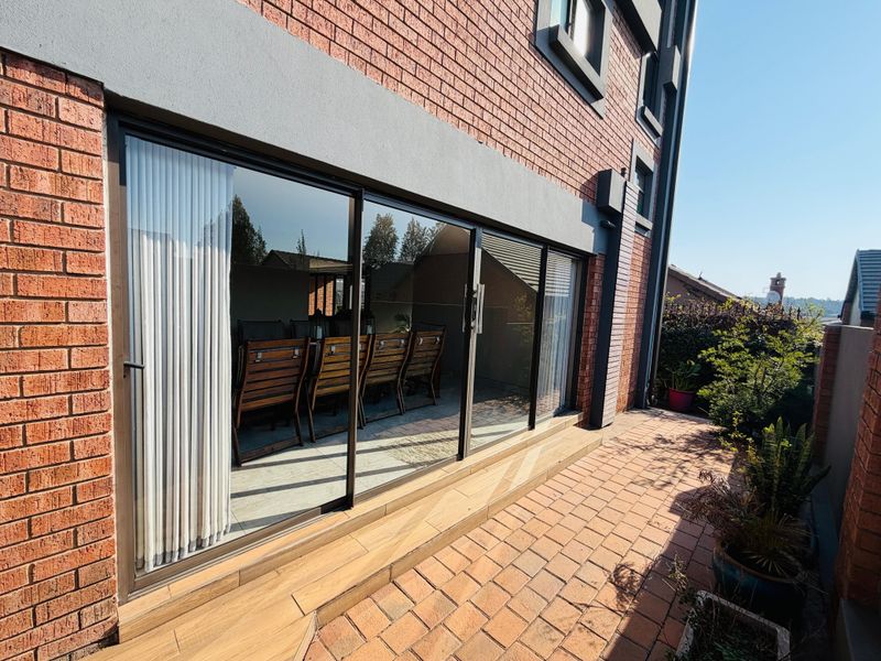 Rear exterior view featuring a brick facade, large sliding glass doors, and a paved patio area.