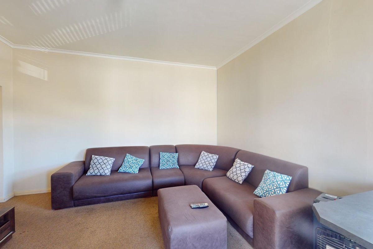 A living room featuring neutral walls, coving, and window blinds, providing a functional and well-lit space.