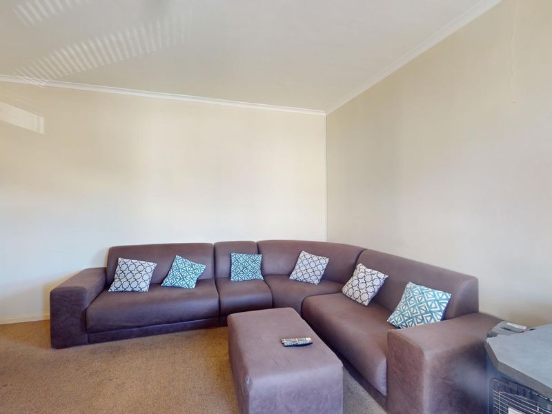 A living room featuring neutral walls, coving, and window blinds, providing a functional and well-lit space.