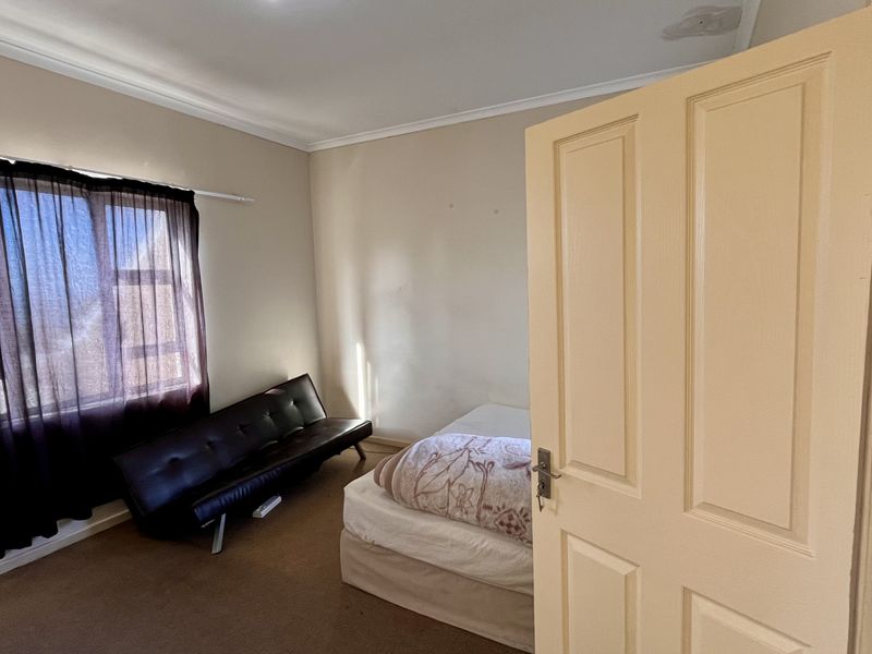 A standard bedroom featuring neutral wall tones, carpeted flooring, and a window with natural light exposure.