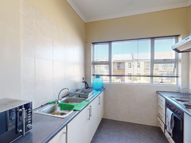A functional kitchen featuring built-in cabinetry, a stainless steel sink, tiled backsplash, and integrated cooking appliances including an oven and hob.
