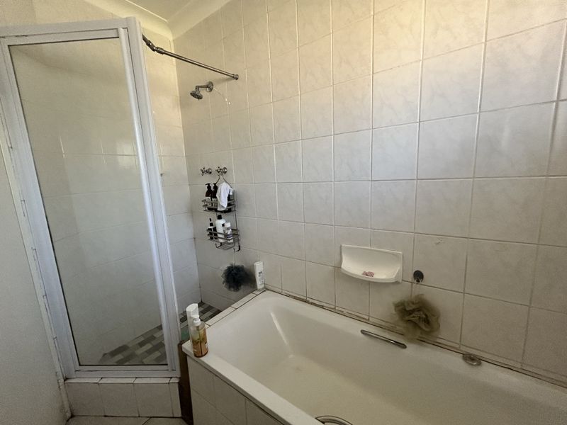 A functional bathroom featuring a built-in bathtub and a separate shower enclosure with white wall tiling.