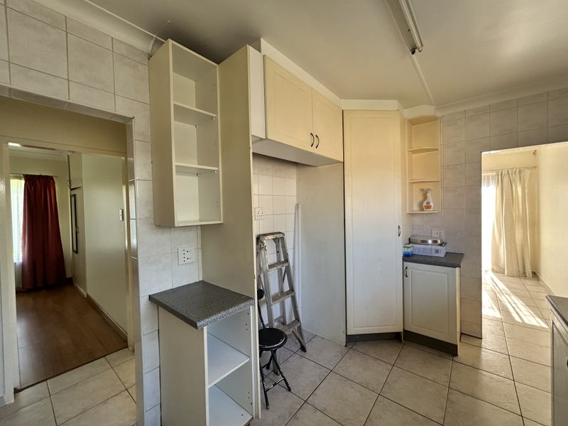A dated kitchen area featuring built-in cabinetry, tiled flooring, and tiled splashbacks, offering a blank canvas for potential renovation and modernization.