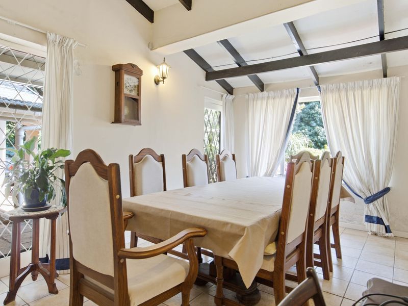 Dining room featuring exposed timber ceiling beams, tiled flooring, and diamond pane windows with access to the outdoor area.