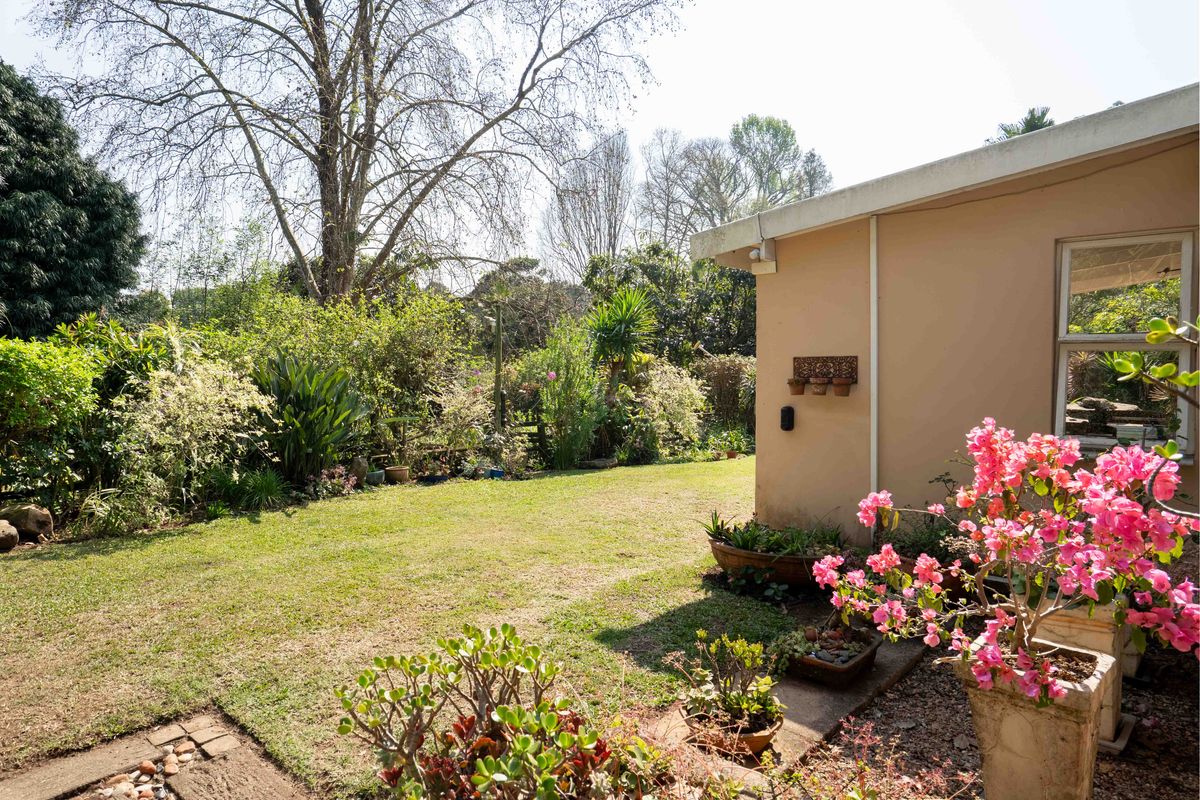 A view of the rear garden featuring a well-maintained lawn and established landscaping adjacent to the property's exterior wall.