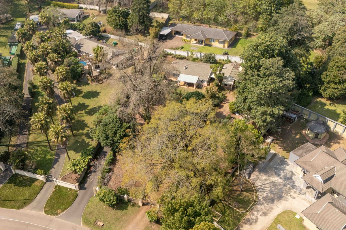 Aerial view of the property showcasing the expansive landscaped garden, paved driveway, and surrounding residential neighborhood layout.