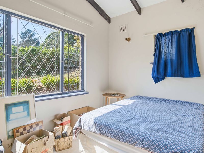 A bedroom featuring exposed timber ceiling beams, security bars on the windows, and a ventilation grille, offering a functional space with natural light.