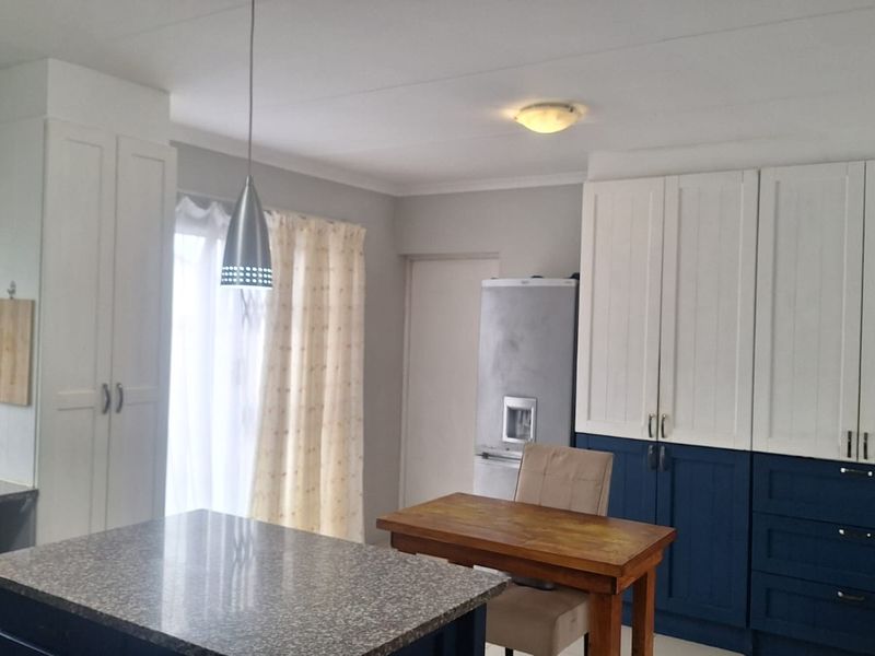 A kitchen featuring two-tone blue and white cabinetry, granite countertops, and modern pendant lighting, offering a functional and stylish workspace.