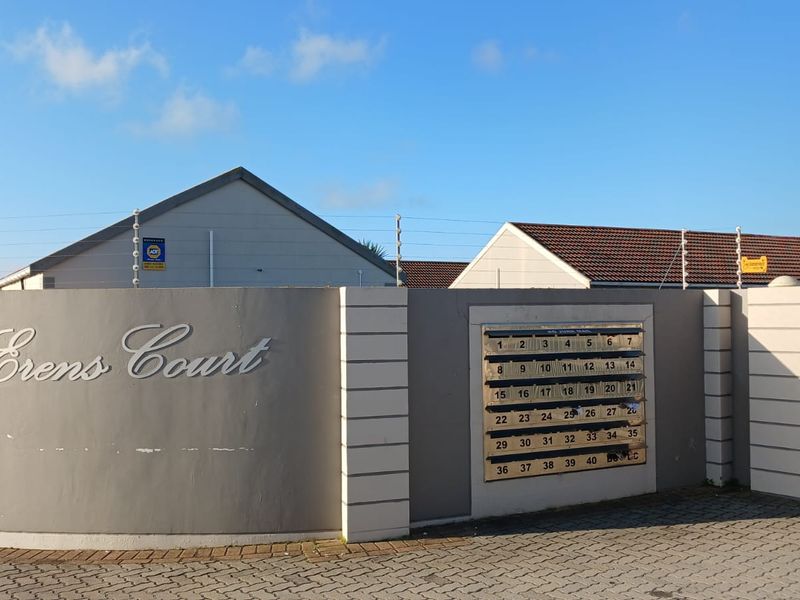 Front entrance view of Erens Court townhouse complex featuring a perimeter wall with electric fencing, communal mailboxes, and gated access.