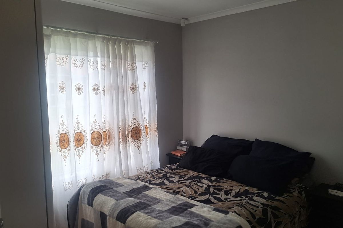 A standard bedroom featuring neutral wall paint, a window with installed curtain rails, and coving detail.