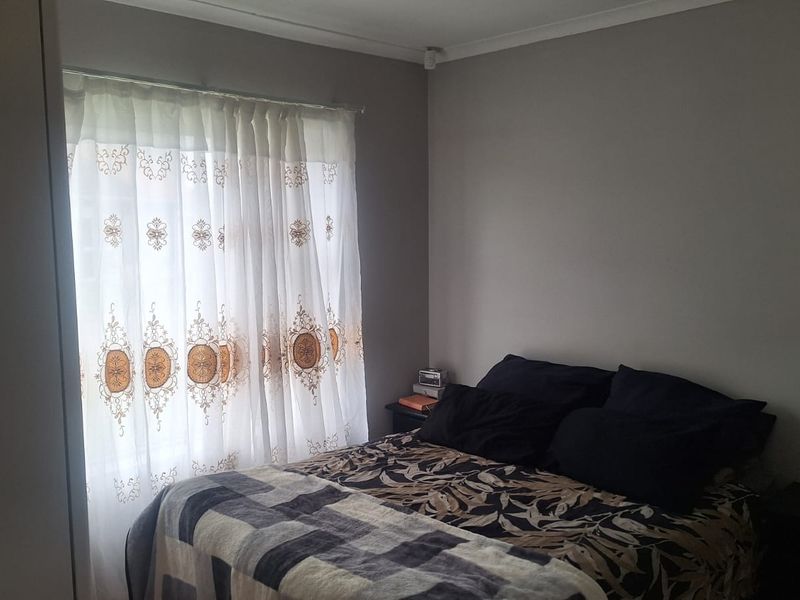 A standard bedroom featuring neutral wall paint, a window with installed curtain rails, and coving detail.