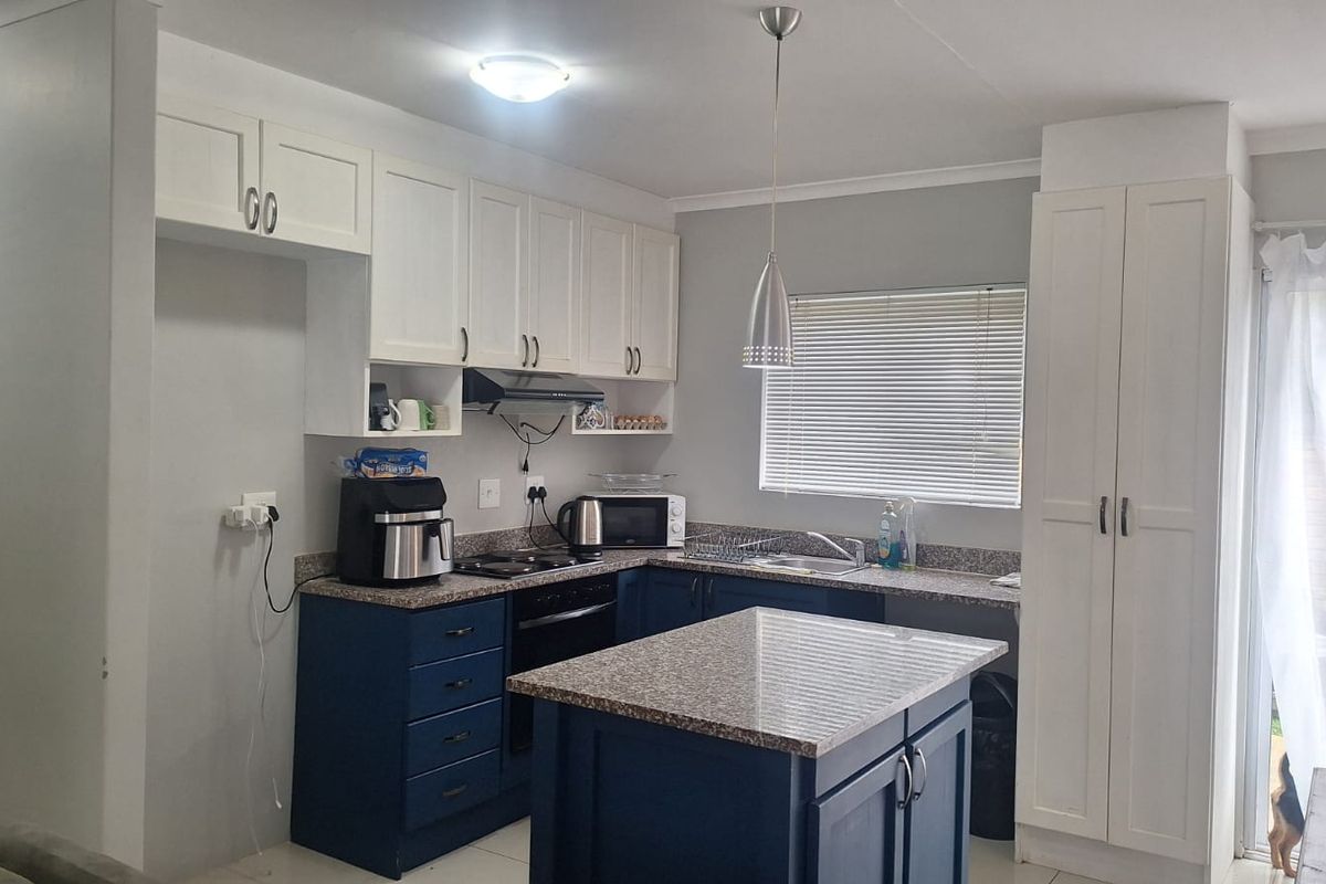 Modern kitchen featuring two-tone cabinetry, granite countertops, a central island, and integrated appliances, offering a functional and stylish cooking space.