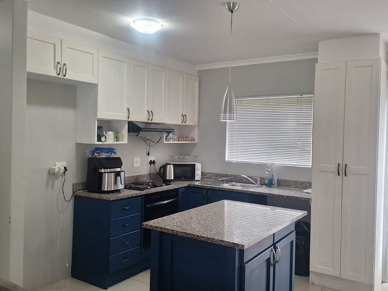 Modern kitchen featuring two-tone cabinetry, granite countertops, a central island, and integrated appliances, offering a functional and stylish cooking space.