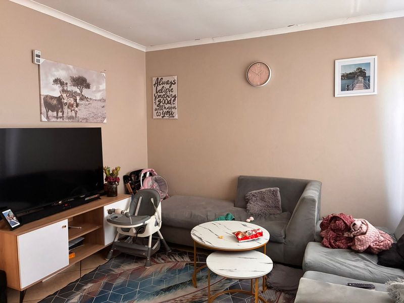 A living room featuring tiled flooring and coving, currently used as a family space.