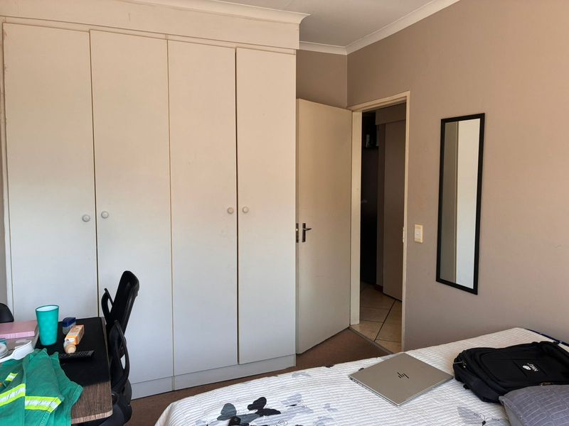 A bedroom featuring built-in cupboards and neutral wall finishes, providing a functional space with direct access to the hallway.