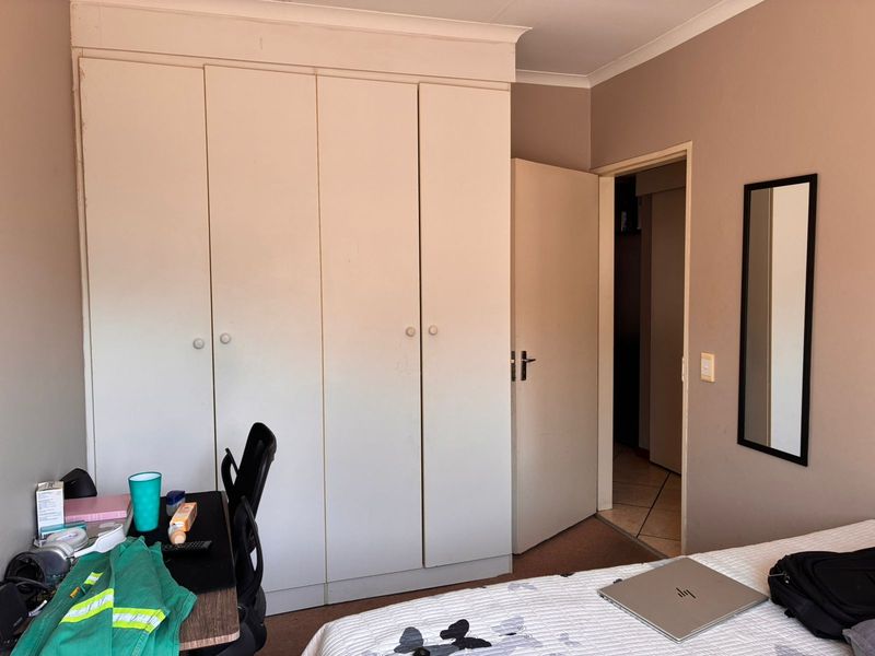 A bedroom featuring built-in cupboards with a neutral wall finish and coving detail, providing functional storage space.