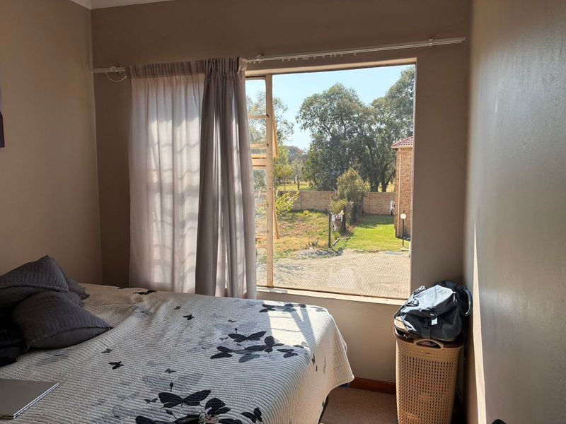 A bedroom featuring a large window with natural light and views of the rear garden area.