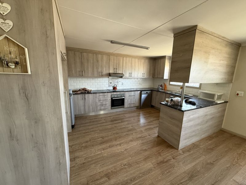 Modern kitchen featuring light wood-grain cabinetry, subway tile backsplash, built-in oven, extractor fan, and a functional breakfast bar with laminate countertops.