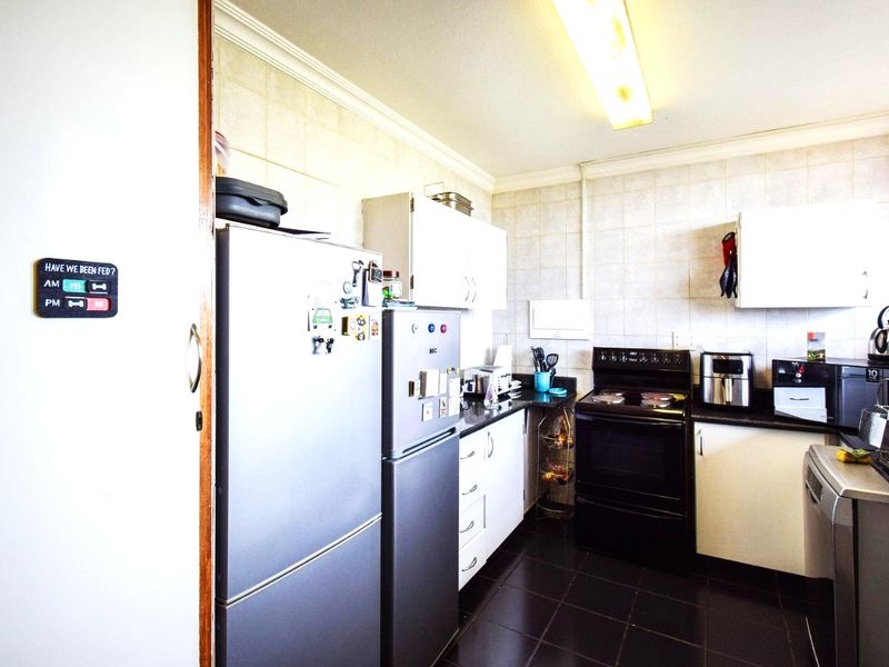 A functional kitchen featuring built-in cabinetry, tiled backsplash, and a freestanding stove, offering a practical layout with potential for modern updates.