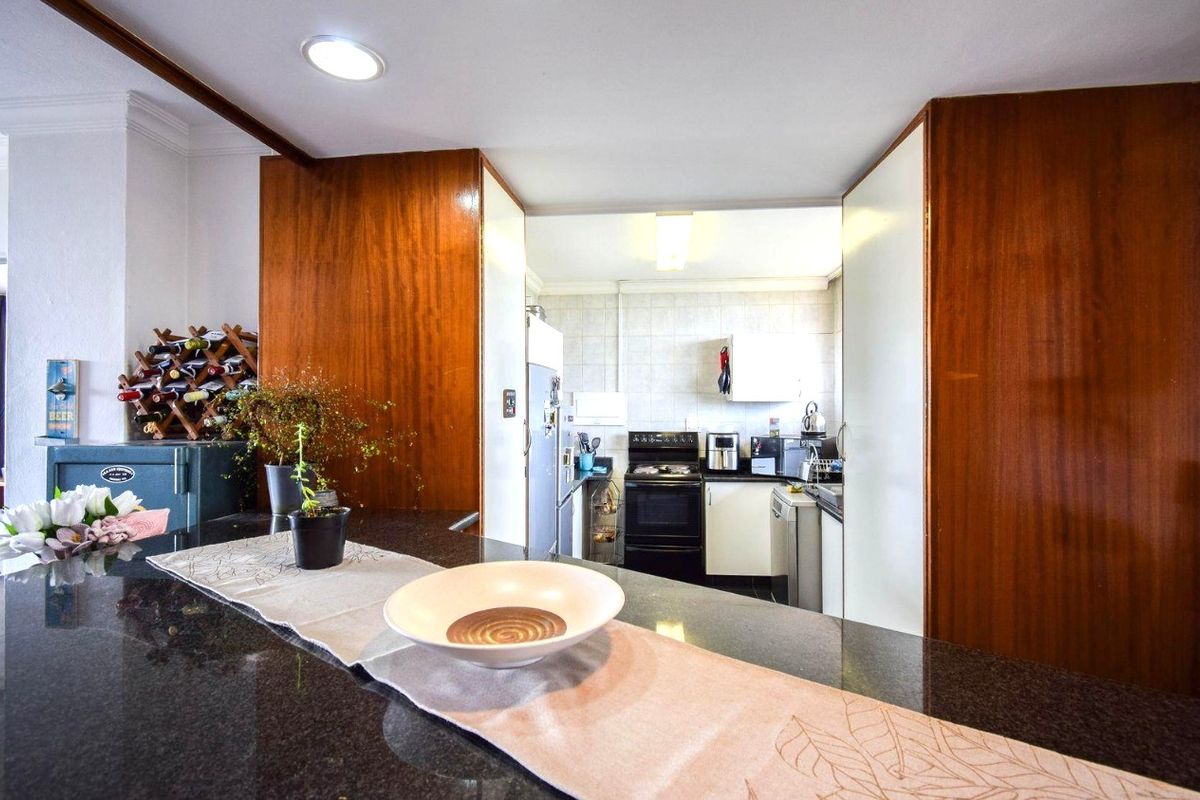 A functional kitchen featuring dark granite countertops, wood-finish cabinetry, and a tiled backsplash, providing a practical workspace with a breakfast bar area.
