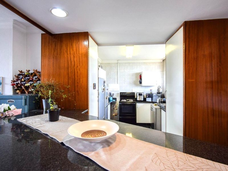 A functional kitchen featuring dark granite countertops, wood-finish cabinetry, and a tiled backsplash, providing a practical workspace with a breakfast bar area.