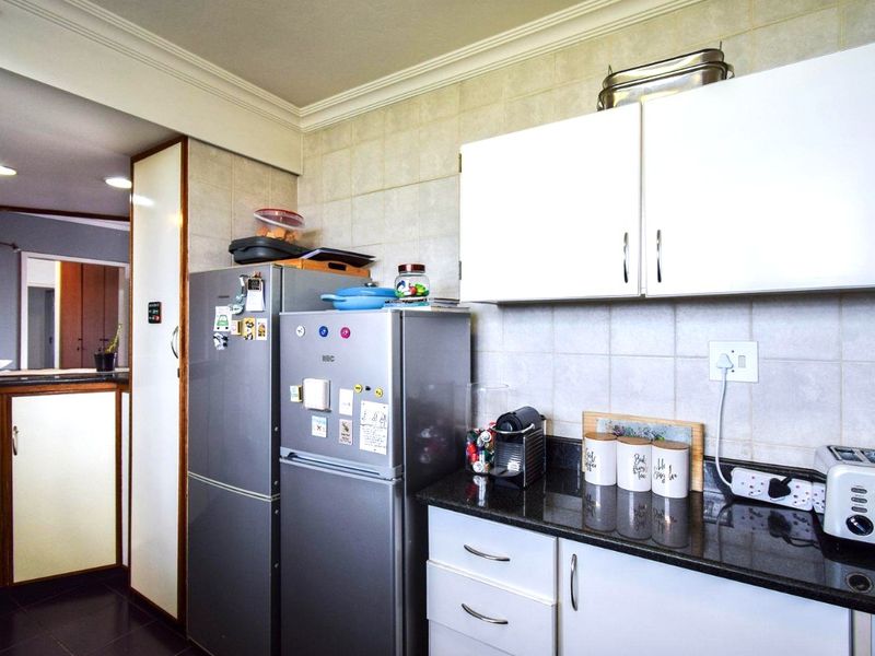 A functional kitchen featuring granite countertops, white cabinetry, and tiled backsplash, providing a practical workspace with integrated storage solutions.