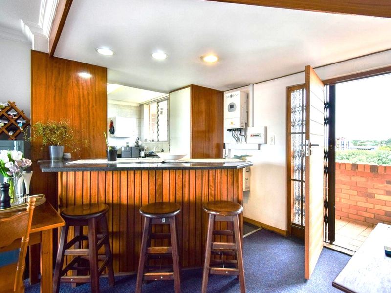 Open plan living area featuring a built-in wooden bar counter, solar inverter installation, and direct access to an outdoor balcony area.