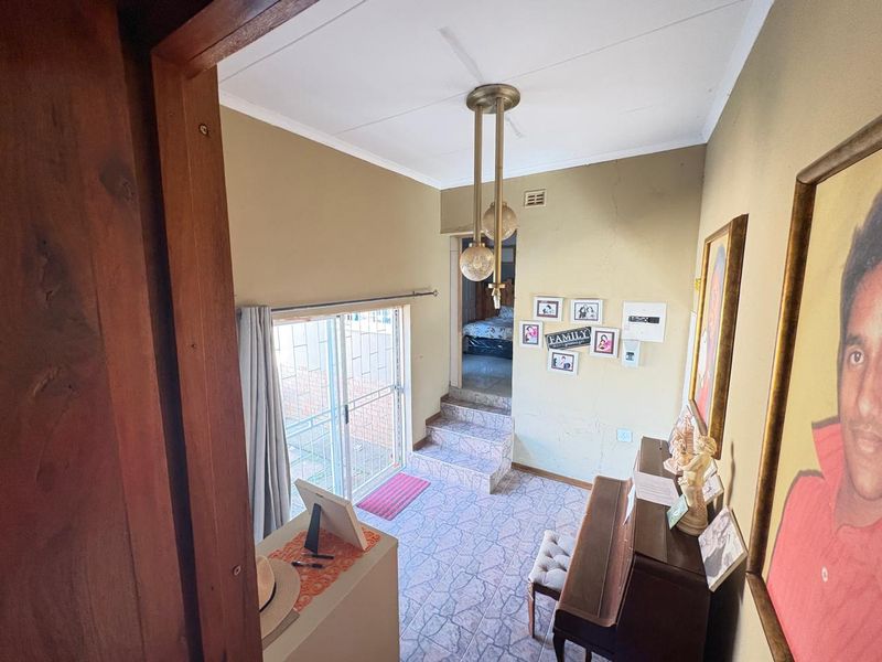 A multi-level living area featuring tiled flooring, a sliding glass door with security gate, and a stepped transition to an adjacent room.