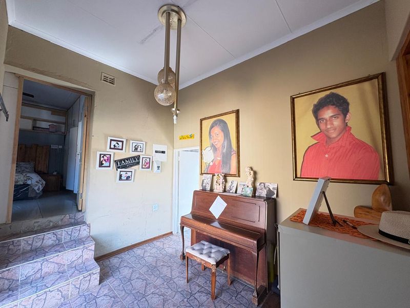 A living area featuring tiled flooring, a raised floor section with tiled steps, and a central pendant light fixture.