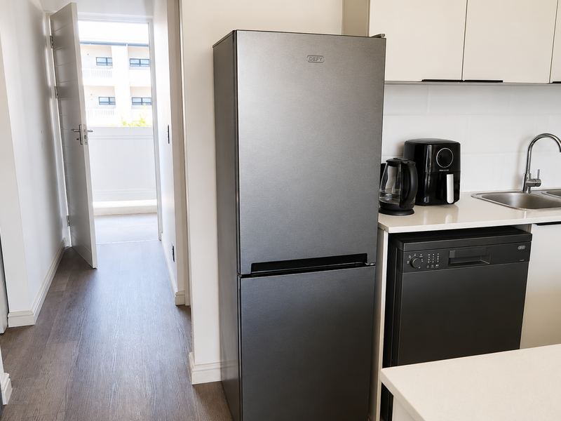 Modern kitchen featuring sleek cabinetry, integrated dishwasher, built-in washing machine, and double sink, with direct access to a balcony.