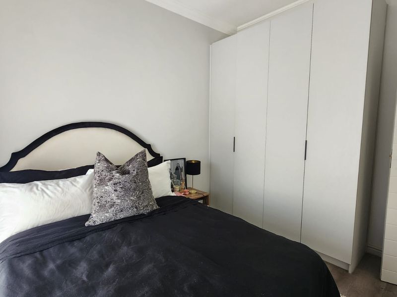 A well-maintained bedroom featuring neutral walls, built-in floor-to-ceiling wardrobes, and a modern internal door.