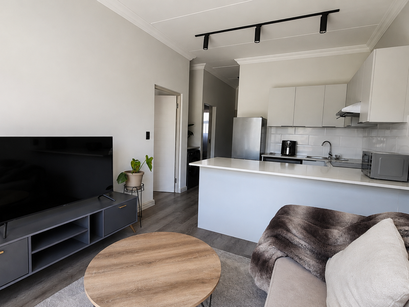 Modern open-plan living area featuring a sleek kitchen with quartz countertops, subway tile backsplash, and contemporary track lighting, seamlessly connected to the lounge space.