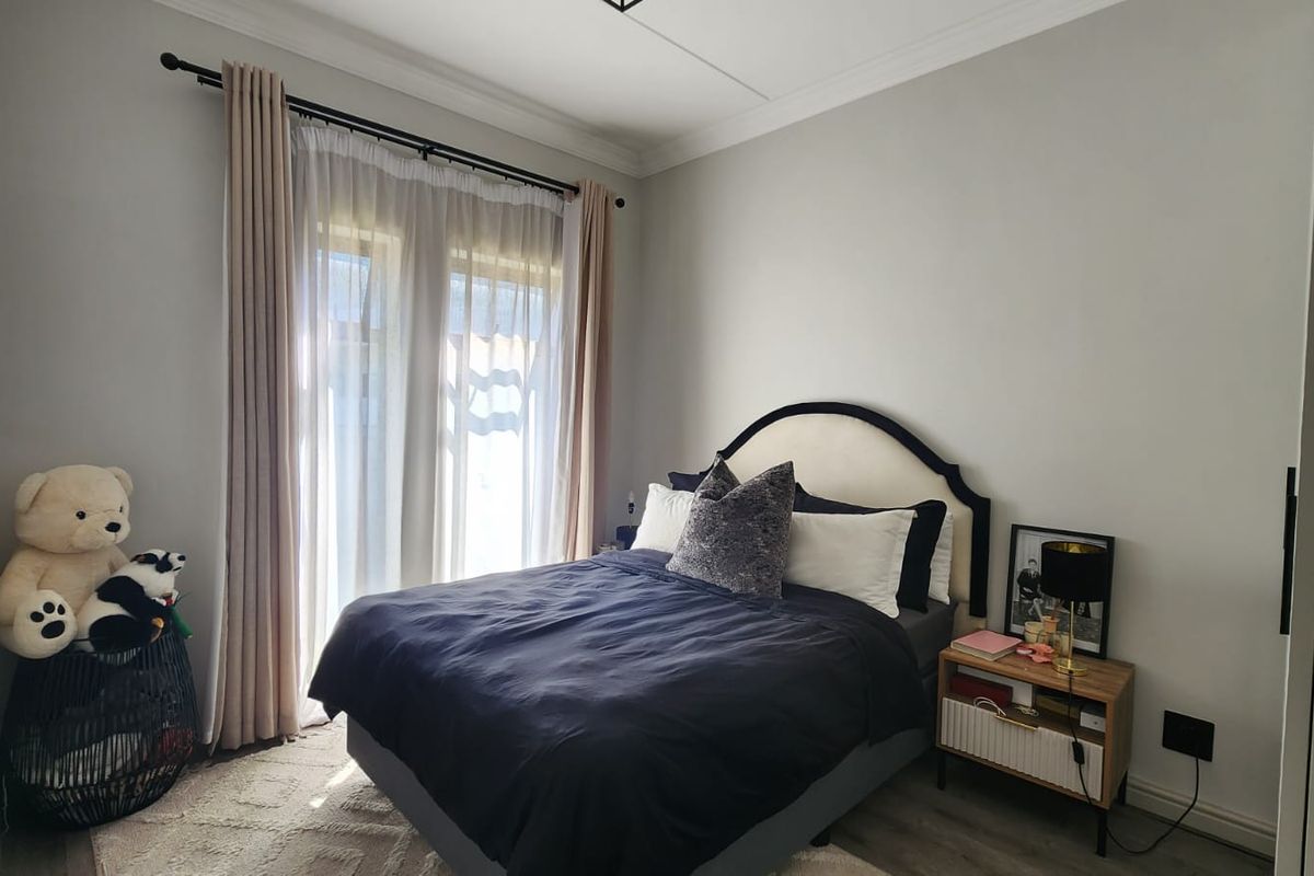 A well-maintained bedroom featuring laminate flooring, crown molding, and a sliding glass door providing natural light.