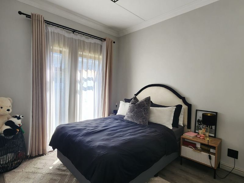 A well-maintained bedroom featuring laminate flooring, crown molding, and a sliding glass door providing natural light.