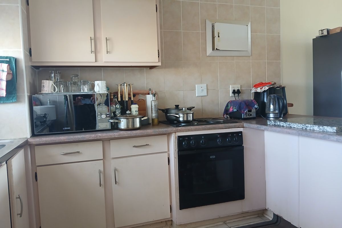 A functional kitchen featuring built-in cabinetry, tiled splashbacks, and a built-in oven with hob, offering a practical layout for daily meal preparation.