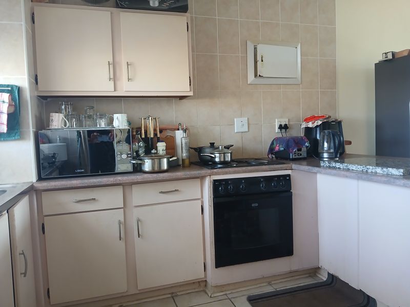 A functional kitchen featuring built-in cabinetry, tiled splashbacks, and a built-in oven with hob, offering a practical layout for daily meal preparation.