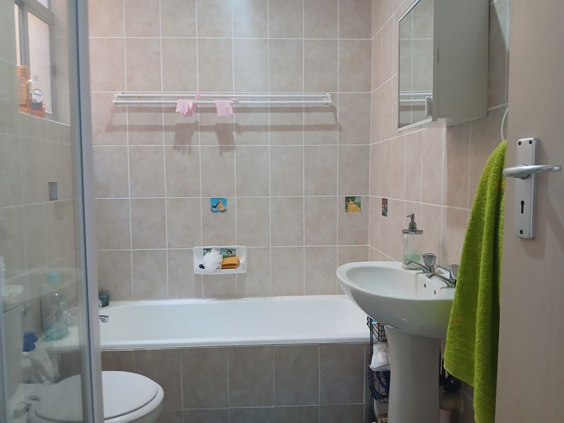 A functional bathroom featuring a bathtub, pedestal basin, and tiled wall finishes with a built-in medicine cabinet.