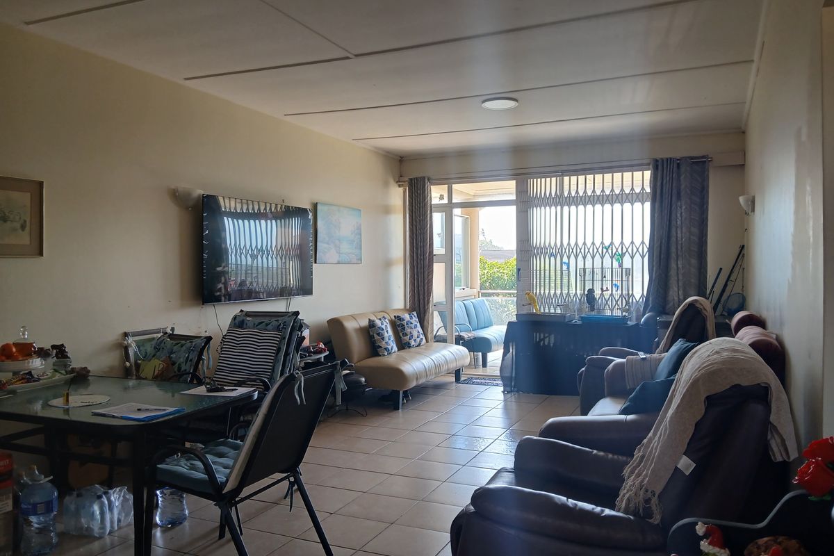 Spacious living room featuring tiled flooring and direct access to a balcony through a sliding glass door with a security gate.