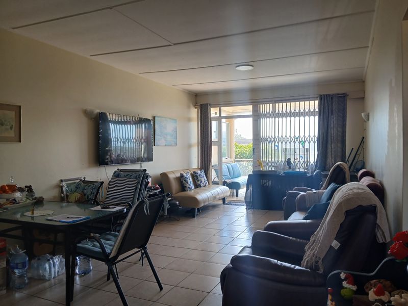 Spacious living room featuring tiled flooring and direct access to a balcony through a sliding glass door with a security gate.