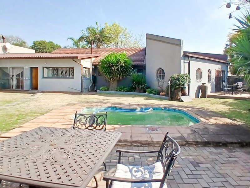 Rear exterior view of the property featuring a swimming pool, paved patio area, and direct access to the home via sliding doors.