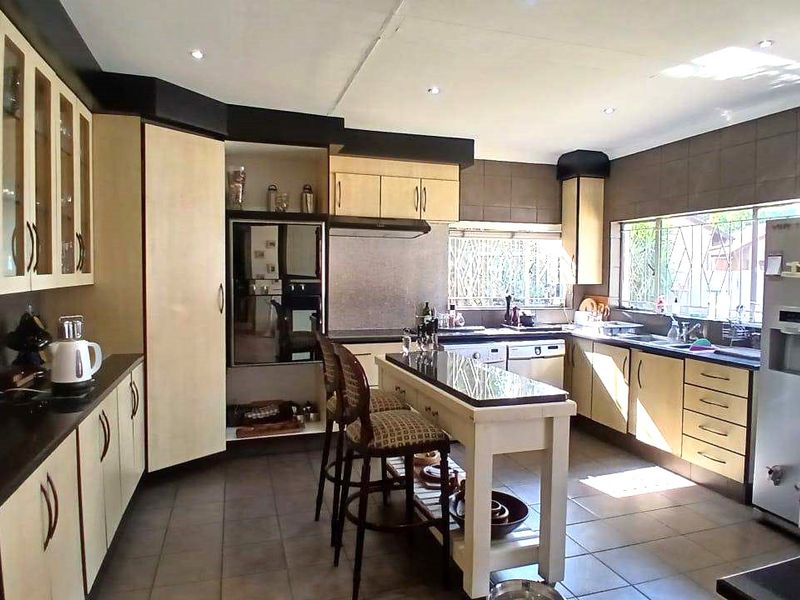 Spacious kitchen featuring extensive built-in cabinetry, granite countertops, tiled flooring, and a central island, offering a functional layout with ample storage space.