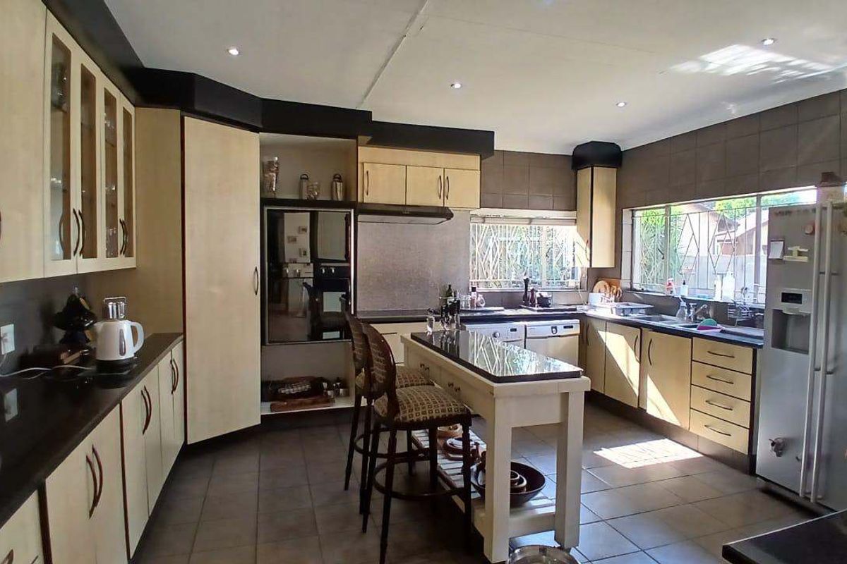 Spacious kitchen featuring built-in cabinetry, granite countertops, a central island, and tiled flooring with ample natural light.