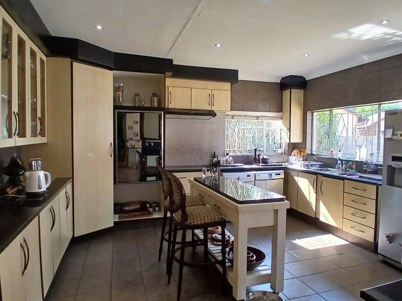 Spacious kitchen featuring built-in cabinetry, granite countertops, a central island, and tiled flooring with ample natural light.