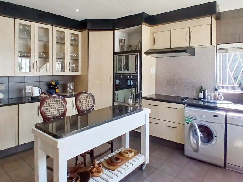 A functional kitchen featuring granite countertops, built-in cabinetry, an extractor fan, and integrated laundry and dishwasher appliances with a tiled backsplash.